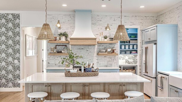 Una cocina moderna con una isla central, taburetes de bar e iluminación colgante.