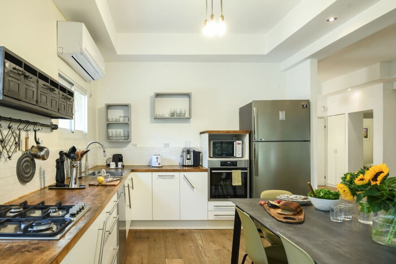 A modern kitchen with a gas stove, microwave, and refrigerator. There is a wooden countertop and a sink.
