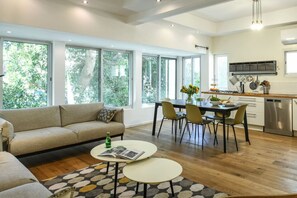 Eine moderne Küche mit großen Fenstern, einem Essbereich mit Tisch und Stühlen, einem Sofa und einem Couchtisch.