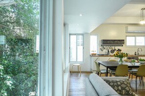 Eine moderne Küche mit Essbereich, einem großen Fenster und Blick auf Grünflächen.