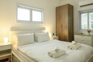 A hotel room with a bed, a wardrobe, a nightstand, and a window with blinds. - Country Vibes in Tel-Aviv by Sea N' Rent (Tel Aviv)