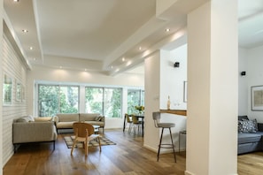 A spacious living area with a sofa, chairs, a dining table, and a kitchen area with a bar. - Country Vibes in Tel-Aviv by Sea N' Rent (Tel Aviv)