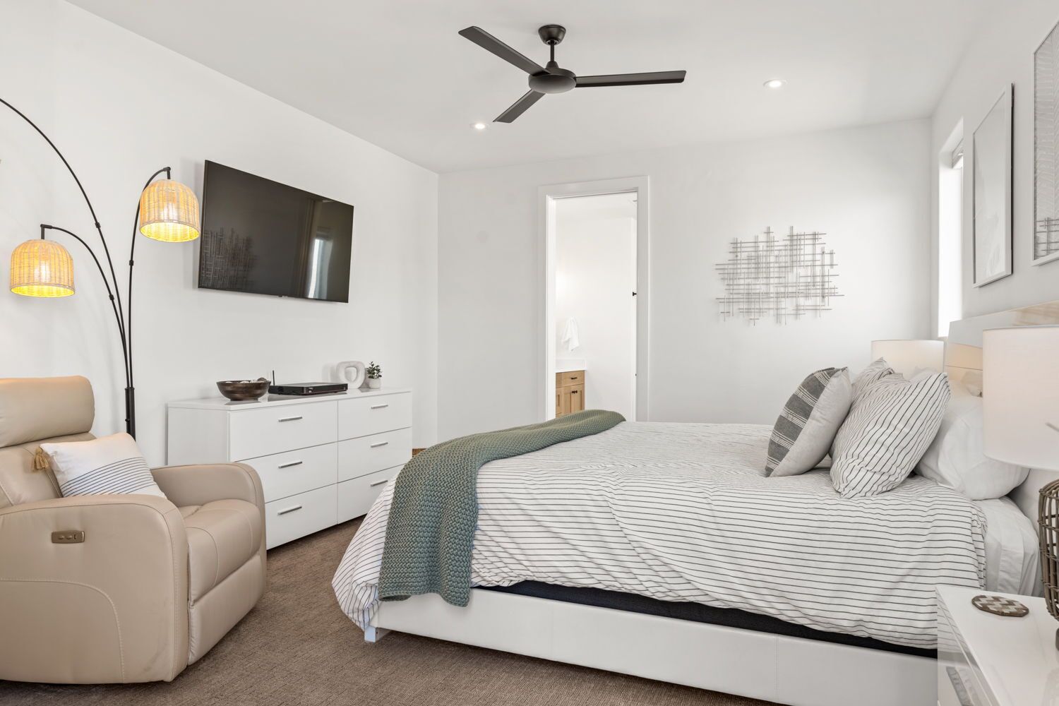 Une chambre moderne équipée d’un lit, d’un canapé, d’une télévision et d’un ventilateur de plafond.