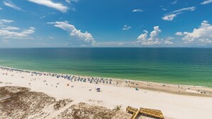 A beach with numerous umbrellas and sun loungers, a sandy shore, and a clear blue sky. - Beautiful Beach Front Condo - Phoenix Gulf Towers 1203 (Orange Beach)