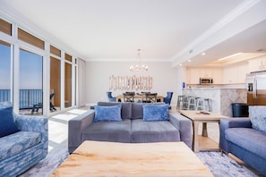 A modern living room with a gray sofa, blue patterned armchair, and a wooden coffee table.