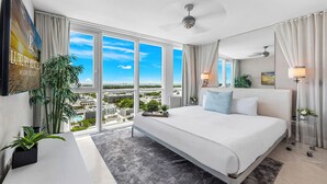 Habitación de hotel moderna con una cama grande, vistas a la ciudad y un balcón.