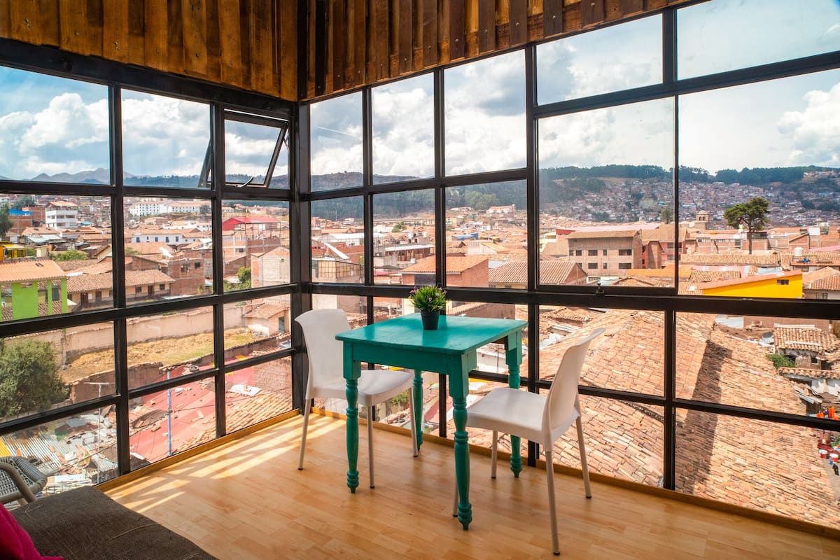 A room with large windows offering a view of a cityscape.
