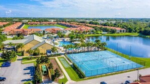 A resort with multiple buildings, a large swimming pool, tennis courts, and a lake. - Resort Townhome with Pool · Game Room & Sauna (Kissimmee)
