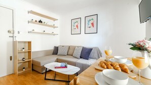 Un saló modern amb un sofà, taula de centre i esmorzar que inclou croissants i suc d'aranja.