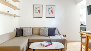 Un saló modern amb un sofà beix, una taula de cafè blanca i dues obres d'art emmarcades a la paret.