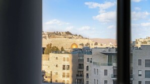 Une vue d’une ville avec des bâtiments modernes et, au loin, une colline surmontée d’une structure en forme de dôme.