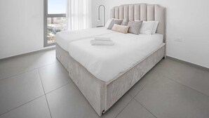 Une chambre moderne avec un grand lit, une vue sur la ville par la fenêtre et un design minimaliste.