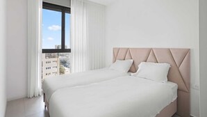 A modern hotel room with a large bed, a view of the city through a window, and a clean, minimalist design. - Tranquil 2Bdr Oasis In The Heart Of Jerusalem (Jerusalem)
