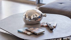 A modern living room with a round coffee table, a metallic decorative object, and a few books and remote controls on it. - Tranquil 2Bdr Oasis In The Heart Of Jerusalem (Jerusalem)