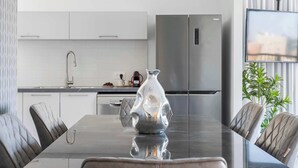 A modern kitchen with white cabinets, stainless steel appliances, and a dining table with leather chairs. - Tranquil 2Bdr Oasis In The Heart Of Jerusalem (Jerusalem)