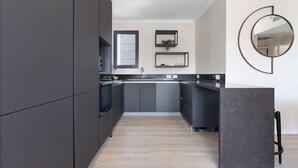 Une cuisine moderne avec des meubles de couleur sombre, un îlot central et un grand miroir rond accroché au mur.