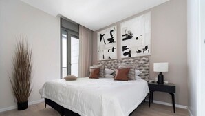 Une chambre à coucher moderne avec un grand lit, une table de chevet et des œuvres d’art abstraites accrochées au mur.