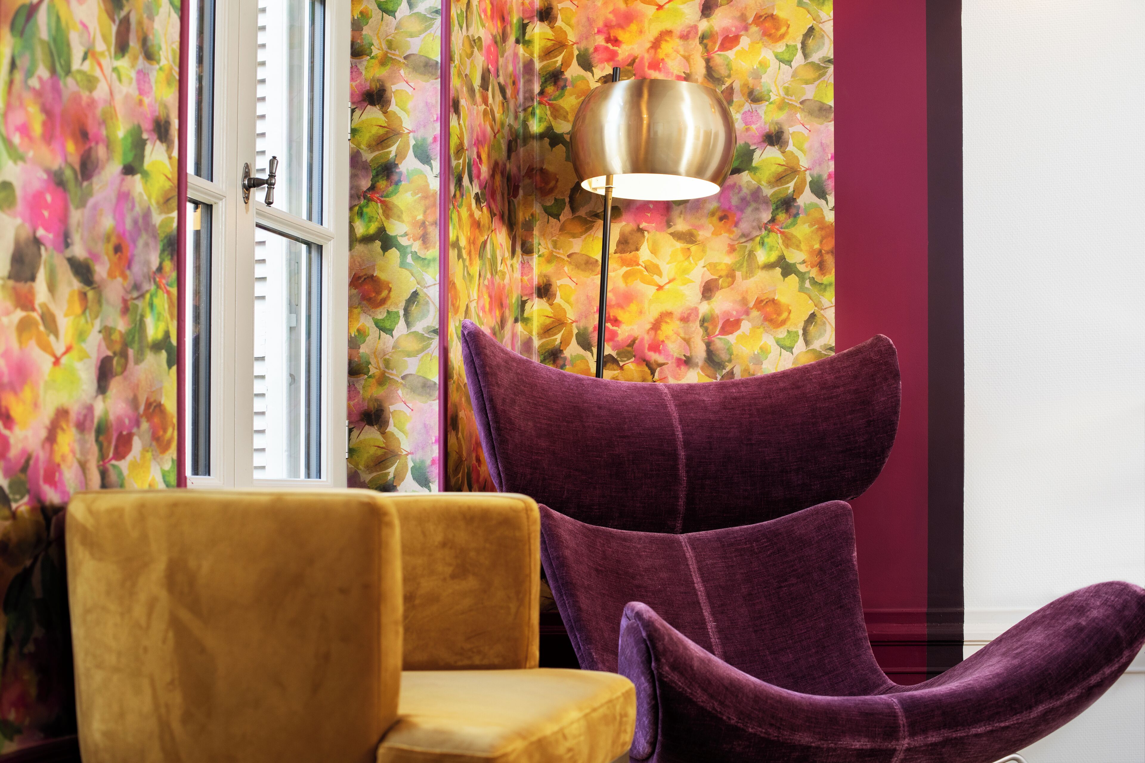 A room with a yellow armchair, a purple chair, and a floor lamp.