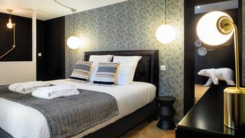 A modern bedroom with a large bed, two bedside lamps, a mirror with a polar bear decoration, and a black nightstand.