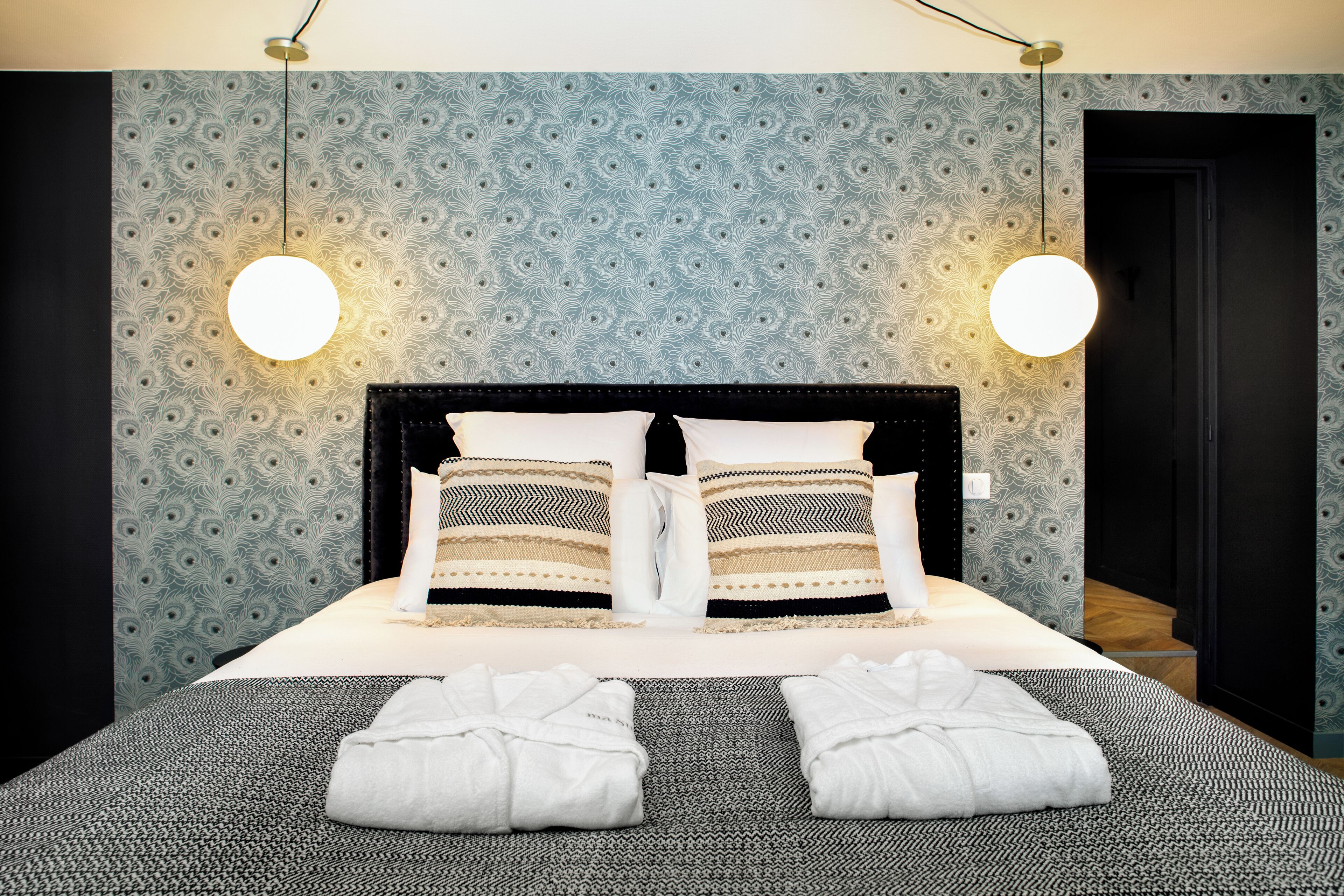 A neatly made bed with two pillows, a bedside table, and two towels.