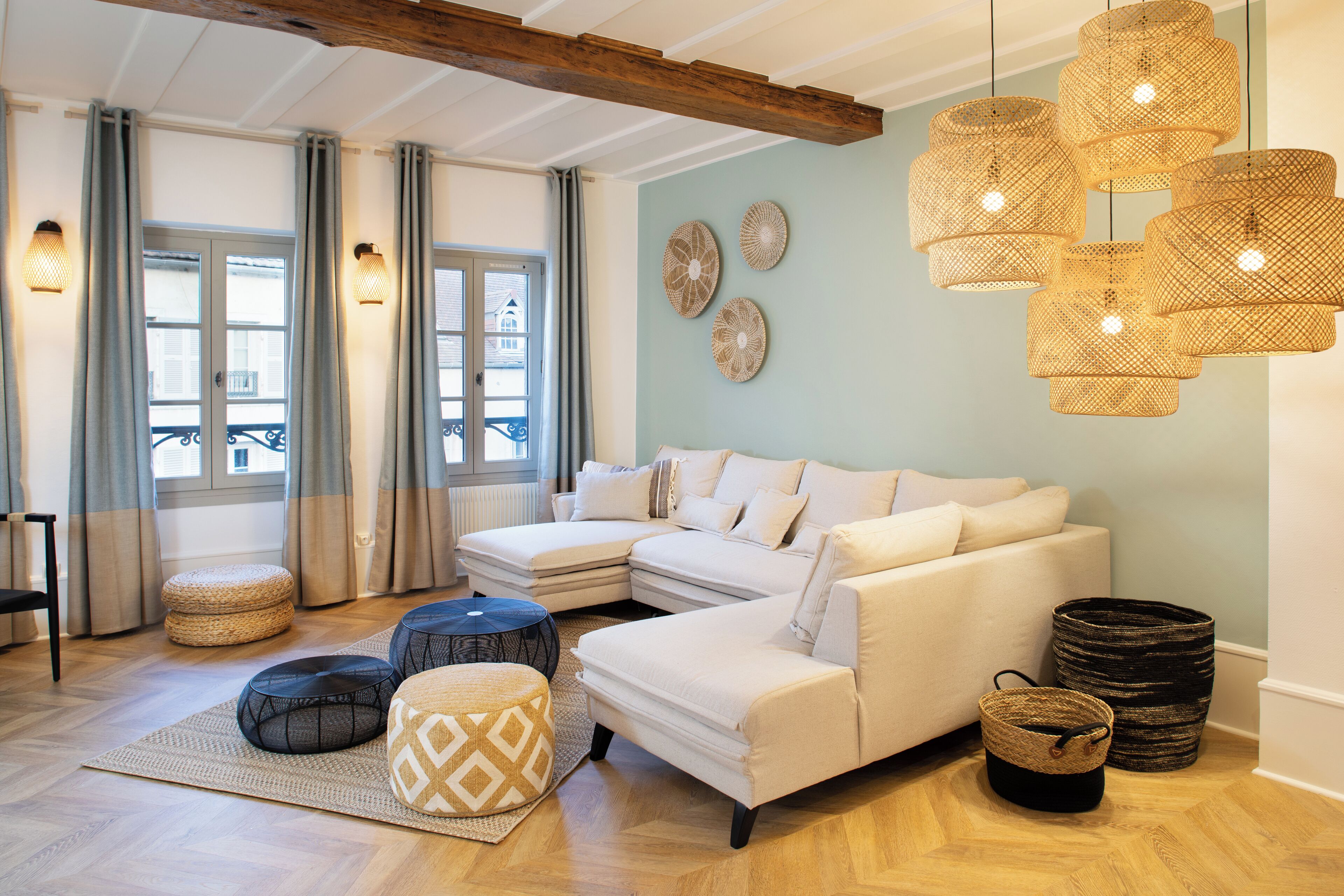A modern living room with a sectional sofa, ottomans, and woven baskets.