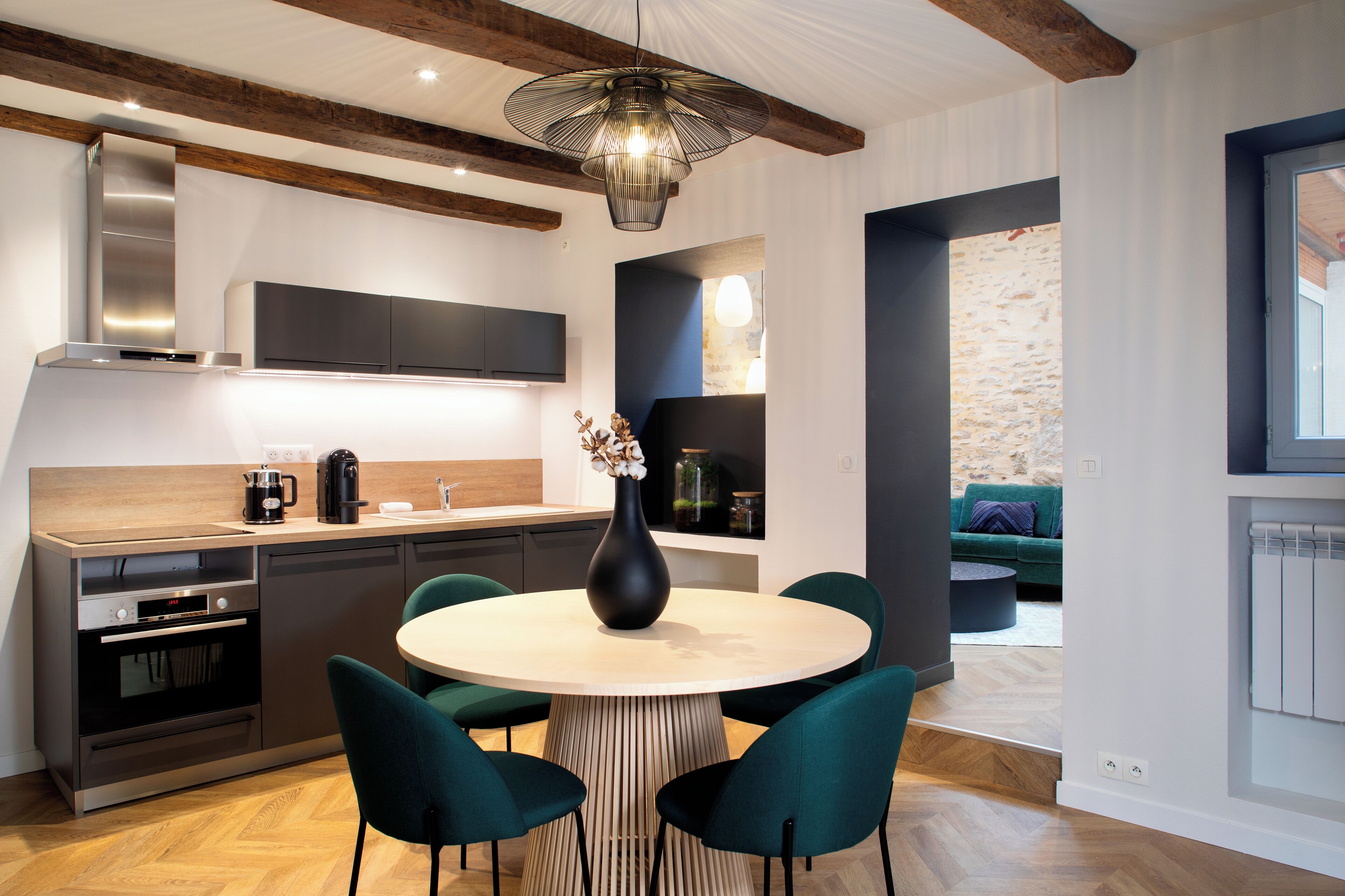 Una cocina moderna con una isla central, electrodomésticos integrados y un comedor con mesa y sillas redondas.