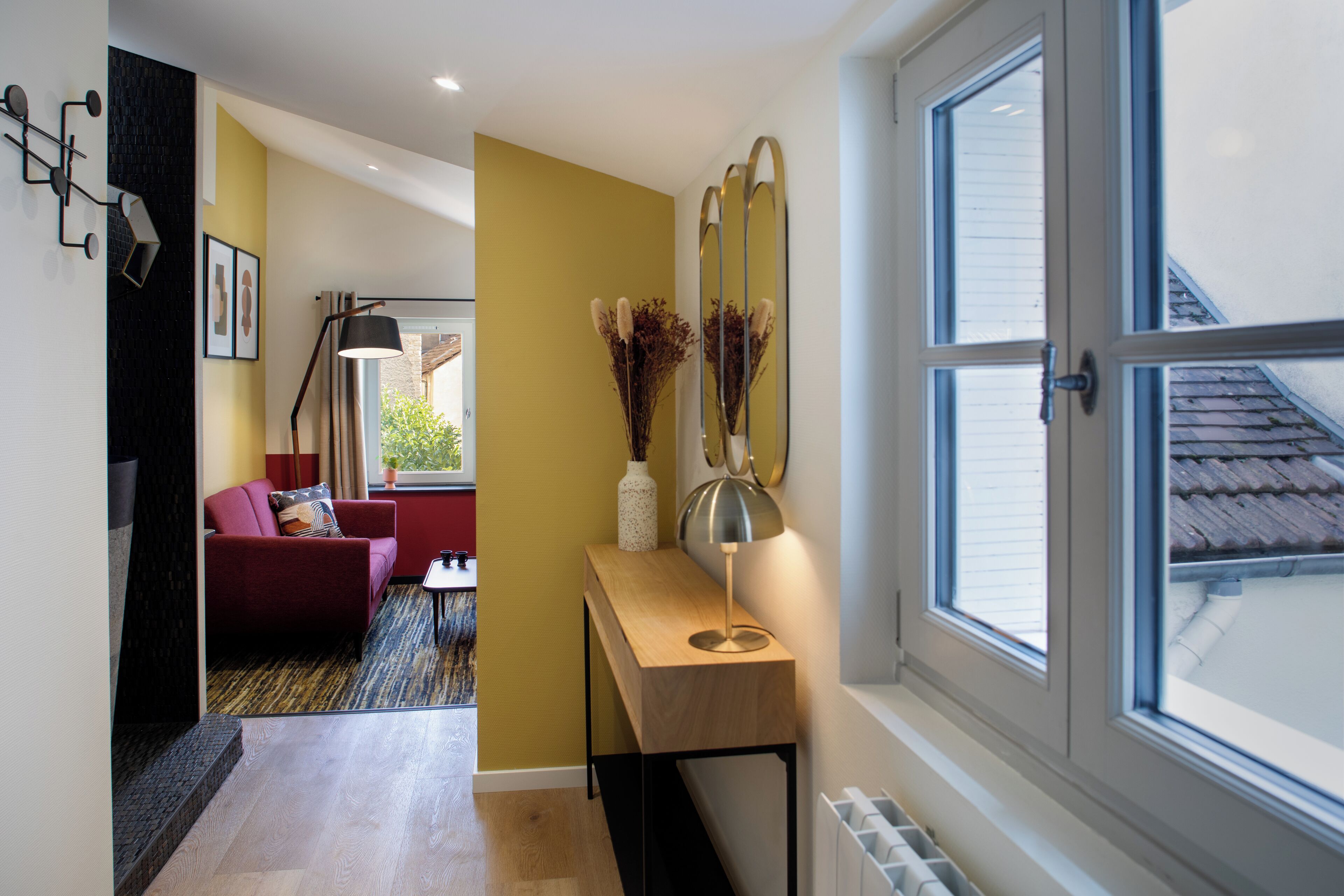 Un salon moderne avec un canapé rouge, une console en bois et un lampadaire.