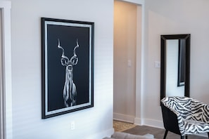 Artwork adorns the walls, complemented by a stylish armchair and large mirror.