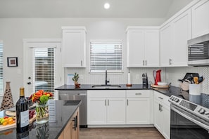 Enjoy cooking in this kitchen with a sink, stainless steel range hood, and ample counter space.