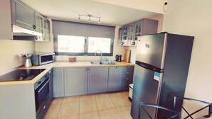 A modern kitchen with grey cabinets, a stainless steel refrigerator, a microwave, and a built-in oven. - Casa Bella Vista - pool - WiFi - Table tennis  (Antigua)