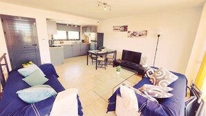 A compact living space with a sofa, a TV, a dining table, and a kitchen area. - Casa Bella Vista - pool - WiFi - Table tennis  (Antigua)