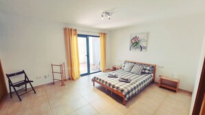 A bedroom with a bed, a chair, a small table, and a window with curtains. - Casa Bella Vista - pool - WiFi - Table tennis  (Antigua)