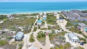 A coastal resort with multiple buildings, a beach, and a clear view of the ocean.