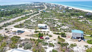An aerial view of a coastal area with multiple buildings, roads, and a beach.