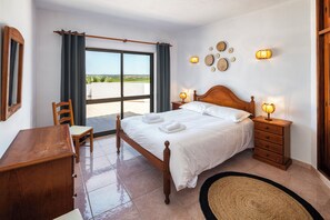 Relax in comfort with a large bed, nightstands, and a desk near a window with a scenic view.