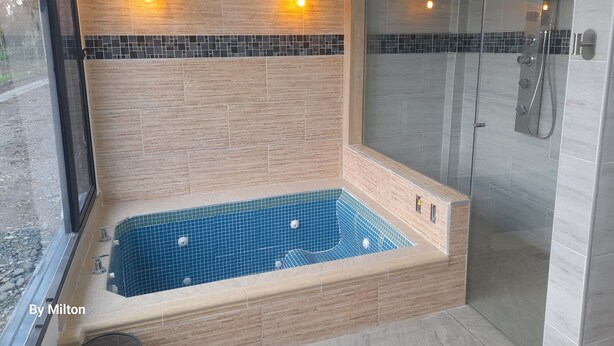 Un baño moderno con una bañera independiente, cabina de ducha con paredes de vidrio y paredes de azulejos.