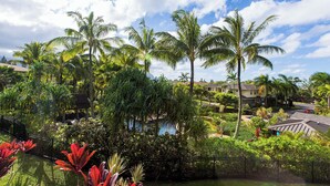 A tropical resort with palm trees, a pool, and a view of the ocean. - Nihilani at Princeville 28B By Parrish Kauai (Princeville)