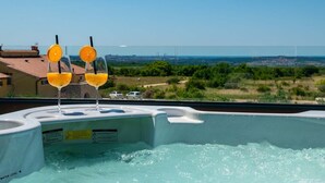 Ein Whirlpool mit drei Gläsern Orangensaft und Blick auf eine Landschaft.