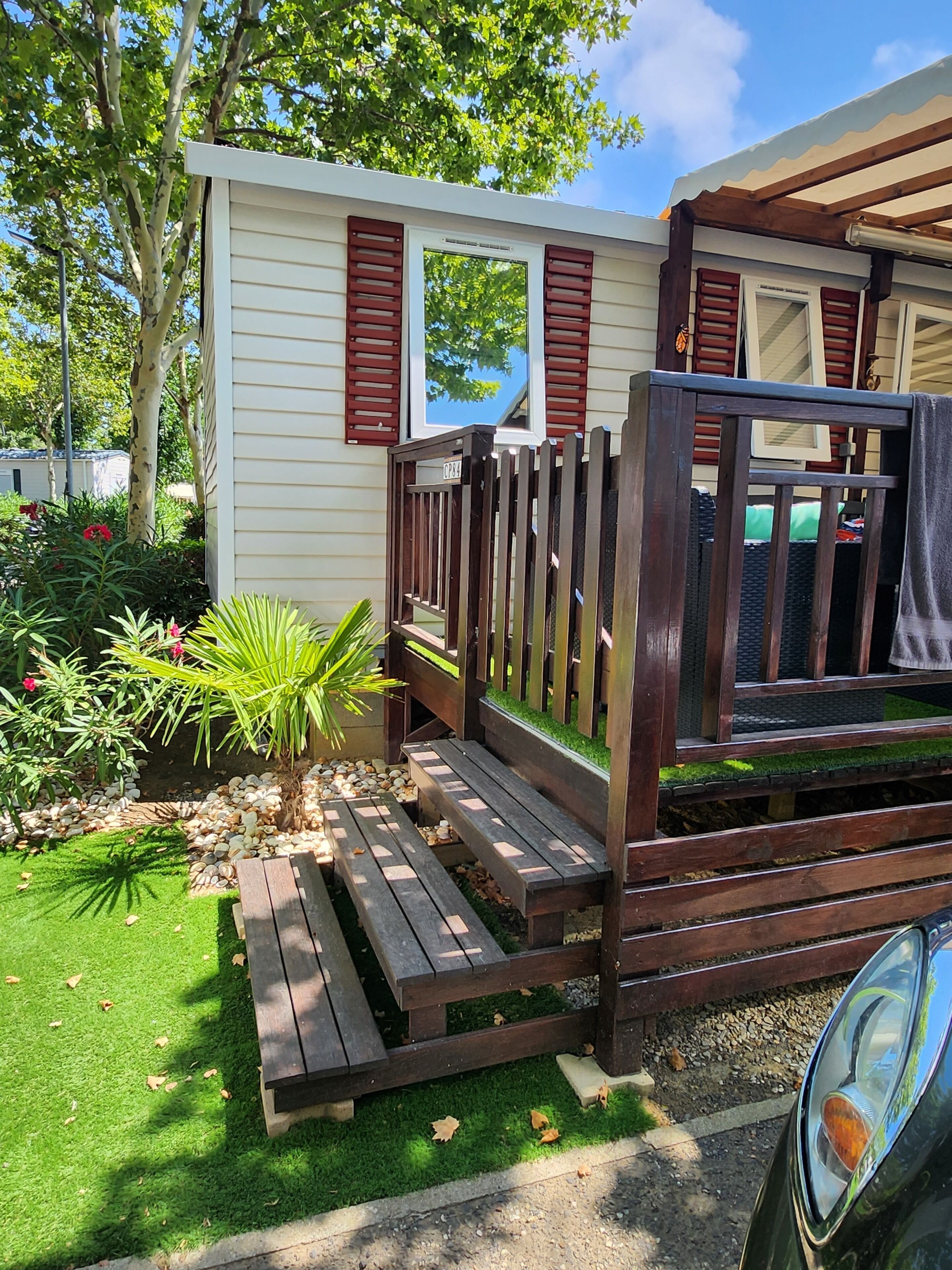 A small house with a wooden deck and a garden.