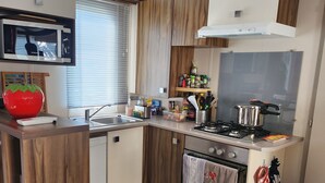 A compact kitchen with wooden cabinets, a built-in oven, a gas stove, and a microwave.