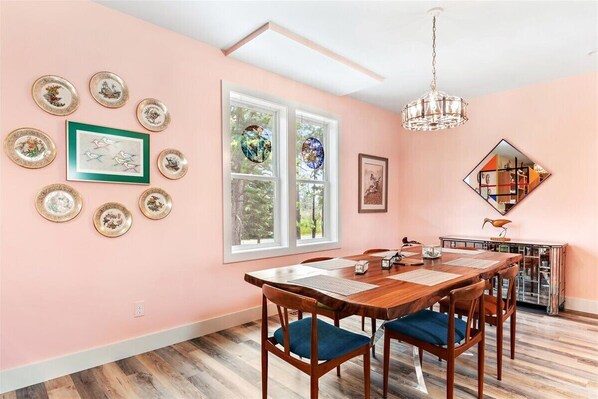 A dining area with a wooden table and chairs, surrounded by walls adorned with framed artwork and decorative plates.
