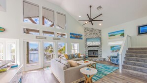 A spacious living room with a high ceiling, large windows, a fireplace, and a staircase. - The Poop Deck: *Pet-friendly *Canalfront *Heated Pool *Sleeps 8 (Anna Maria)