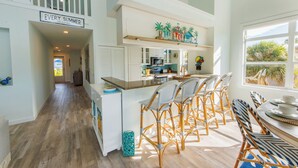 A spacious kitchen with a central island, white cabinetry, and a dining area with wicker chairs. - The Poop Deck: *Pet-friendly *Canalfront *Heated Pool *Sleeps 8 (Anna Maria)