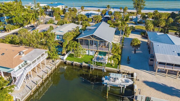 A coastal resort with multiple buildings, a marina, and a view of the ocean. - The Poop Deck: *Pet-friendly *Canalfront *Heated Pool *Sleeps 8 (Anna Maria)