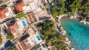 An aerial view of a coastal residential area with houses, swimming pools, and a clear turquoise sea. - Luxury Villa Leisure Seaside Brac with Pool (Milna)