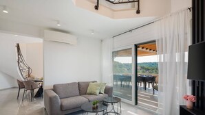 A modern living room with a sofa, two side tables, a flat-screen TV, and a balcony with a table and chairs. - Luxury Villa Leisure Seaside Brac with Pool (Milna)