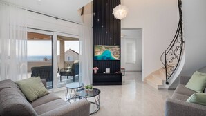 A modern living room with a TV, sofa, and a staircase. - Luxury Villa Leisure Seaside Brac with Pool (Milna)