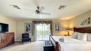 A hotel room with a large bed, a flat-screen TV, a ceiling fan, and a view of the outdoors. - 4 Bed 4 Bath With Private Pool/spa 4 Bedroom Home by RedAwning (Davenport)