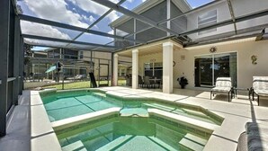 A covered outdoor swimming pool with a patio area, lounge chairs, and a view of the house. - 4 Bed 4 Bath With Private Pool/spa 4 Bedroom Home by RedAwning (Davenport)