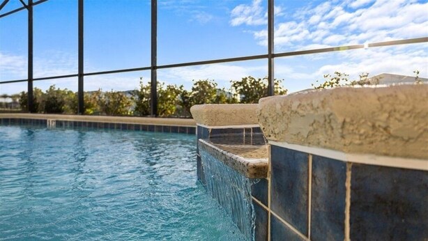 A swimming pool with clear blue water, surrounded by a tiled edge and a stone ledge. - Large 7 Bed In Solterra Pool, Spa Near Disney 7 Bedroom Home by RedAwning (Davenport)